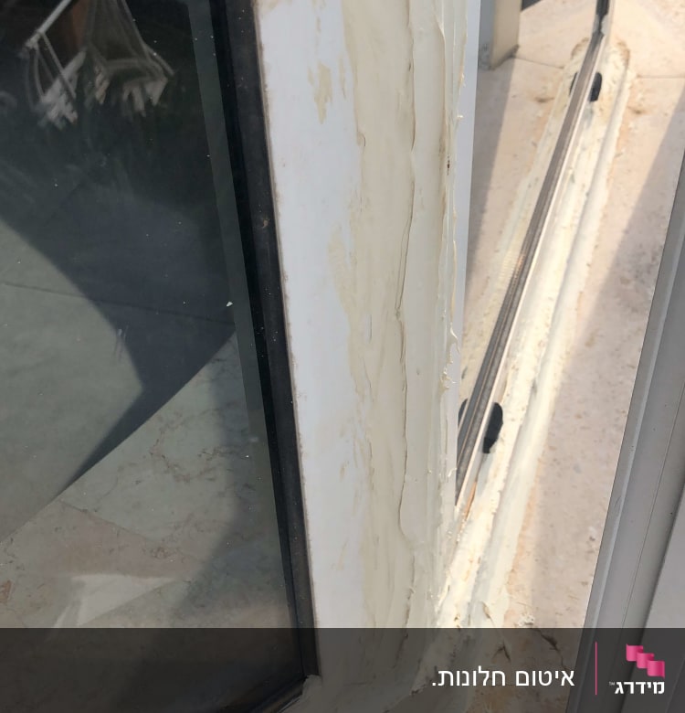 חלון עם תריסים ומסגרת לבנה, אטום בחומר איטום